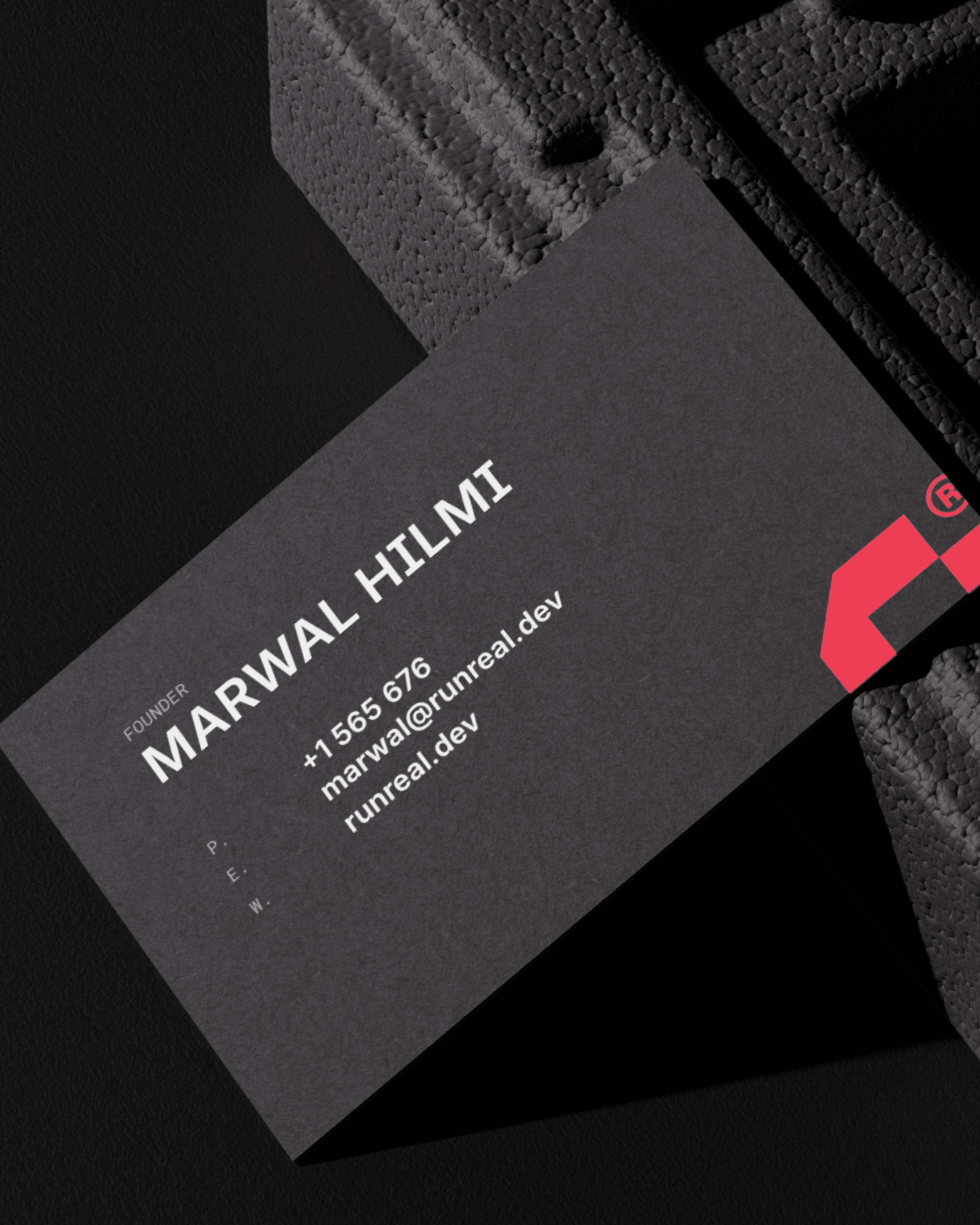 Close-up of a dark Runreal business card for founder Marwal Hilmi with bold white typography and a red geometric logo, designed by Kundo Studio to showcase the tech-forward brand identity and print collateral system.